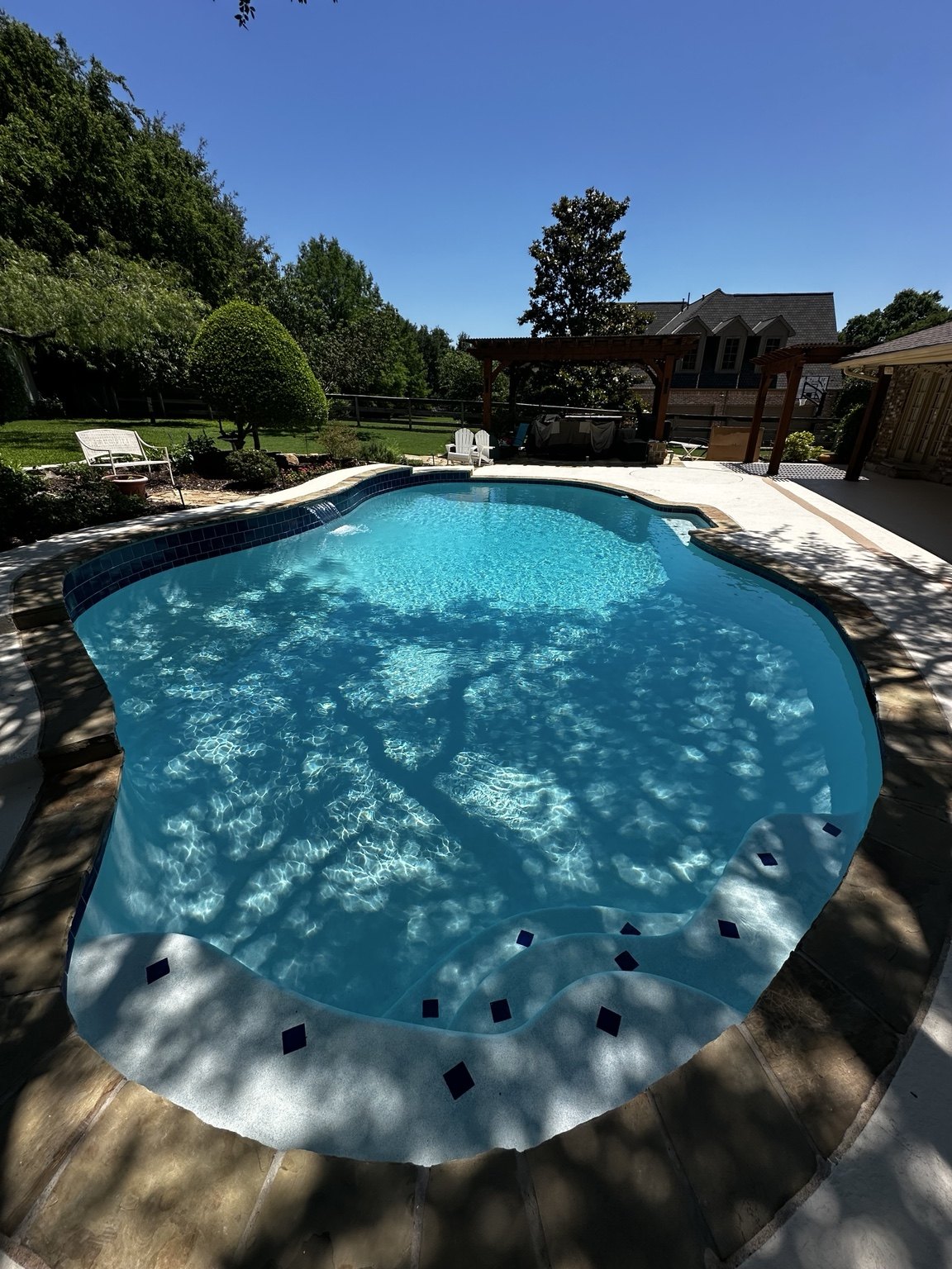 Pool with curved steps, accent tile and a raised water feature