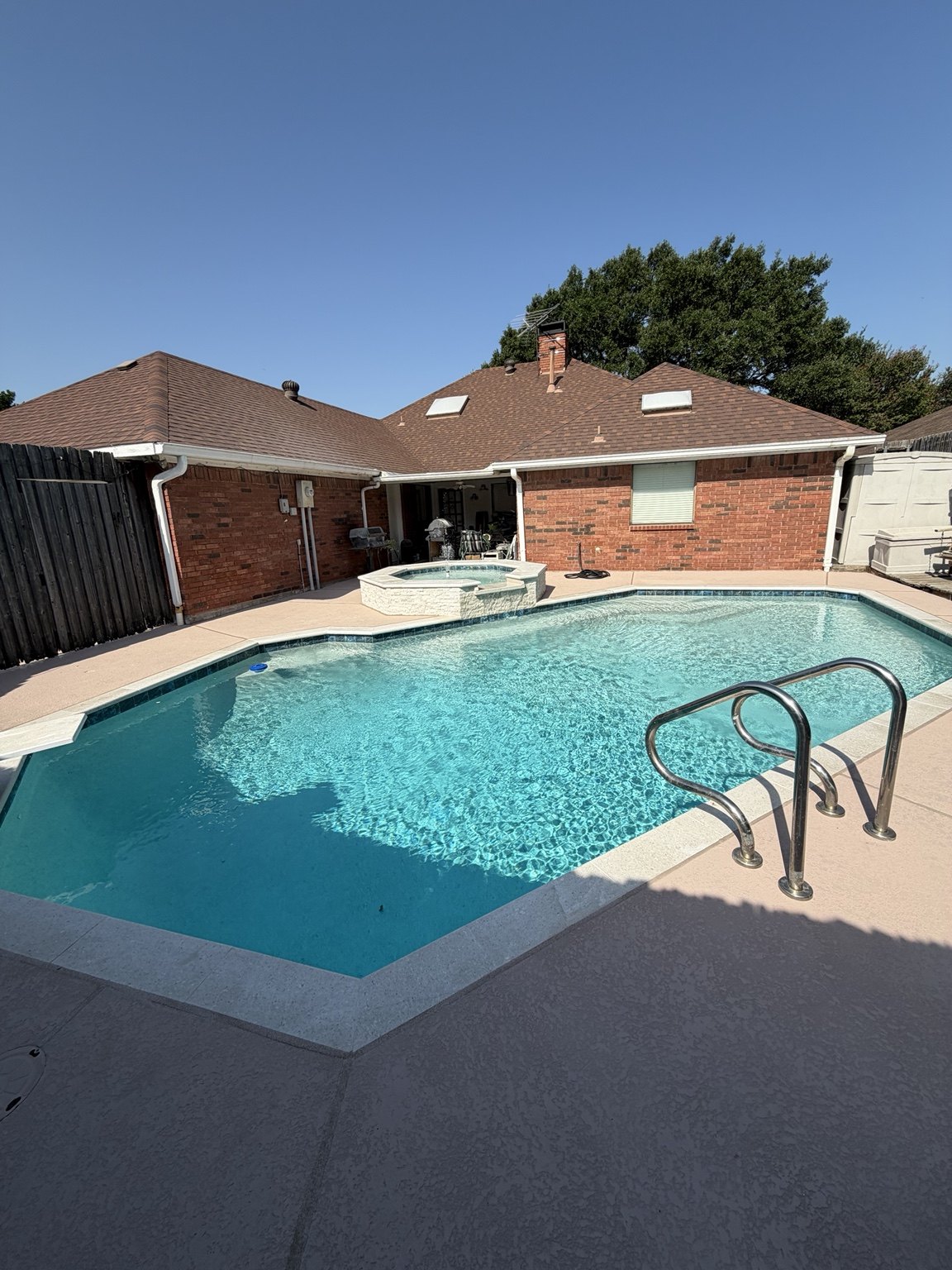 Completed pool and raised spa transformation with clear blue water, light coping and stone spa facing